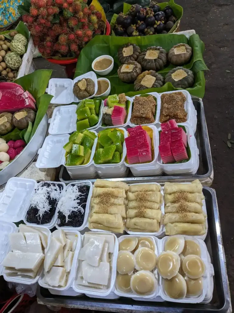 Traditional Cambodian Desserts at Kampot Market Assorted Cambodian desserts and fruits displayed at a market stall in Kampot.