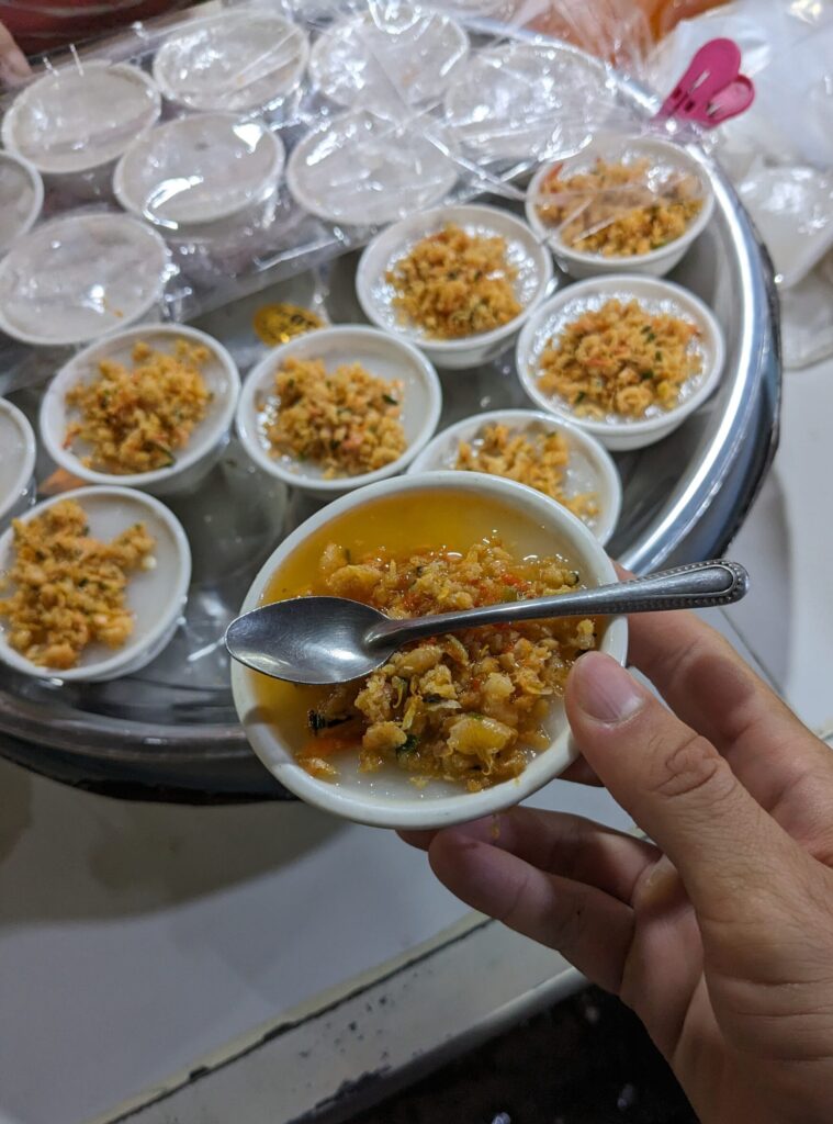 Knom Chan – Cambodian Steamed Rice Cake Knom Chan, a Cambodian steamed rice cake dessert, served in small bowls with savory dried shrimp topping.