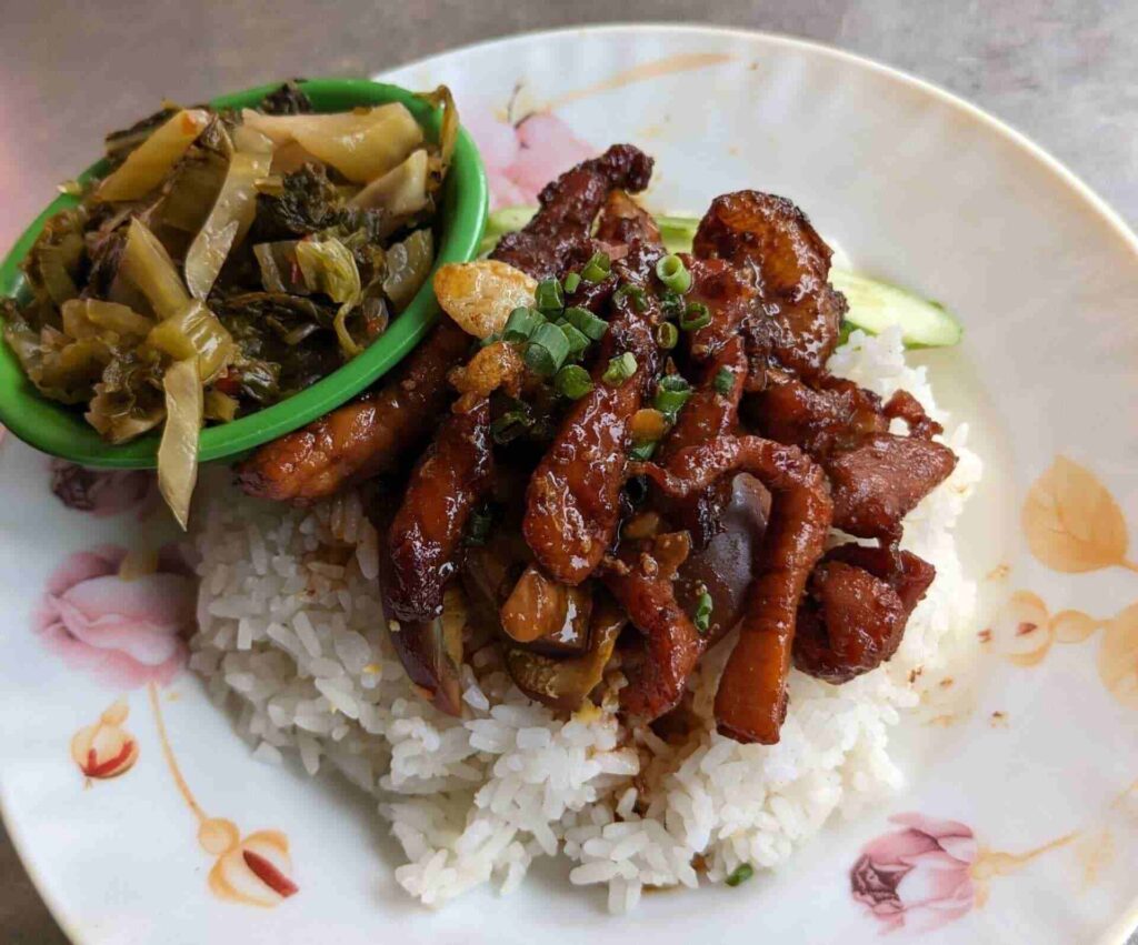 Cambodian pork barbecue served with white rice and pickled greens in Krong Battambang