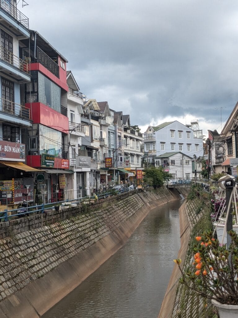Quiet Đà Lạt street lined with flowers along a canal
