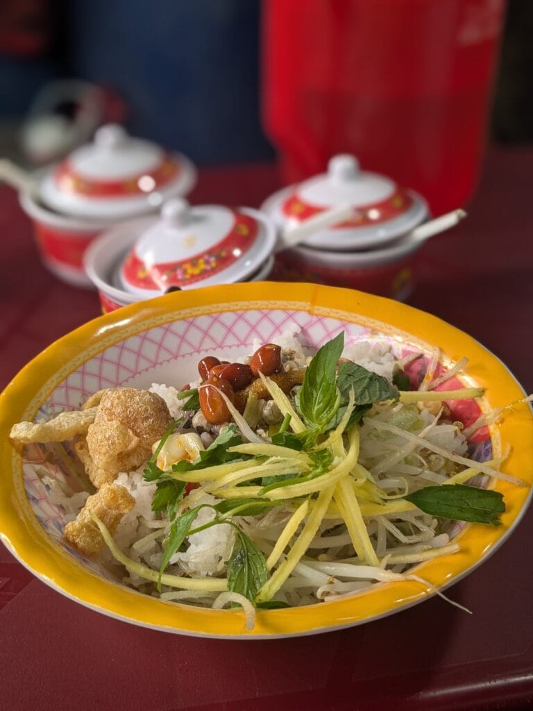 Bowl of Cơm hến with clams, herbs, and peanuts