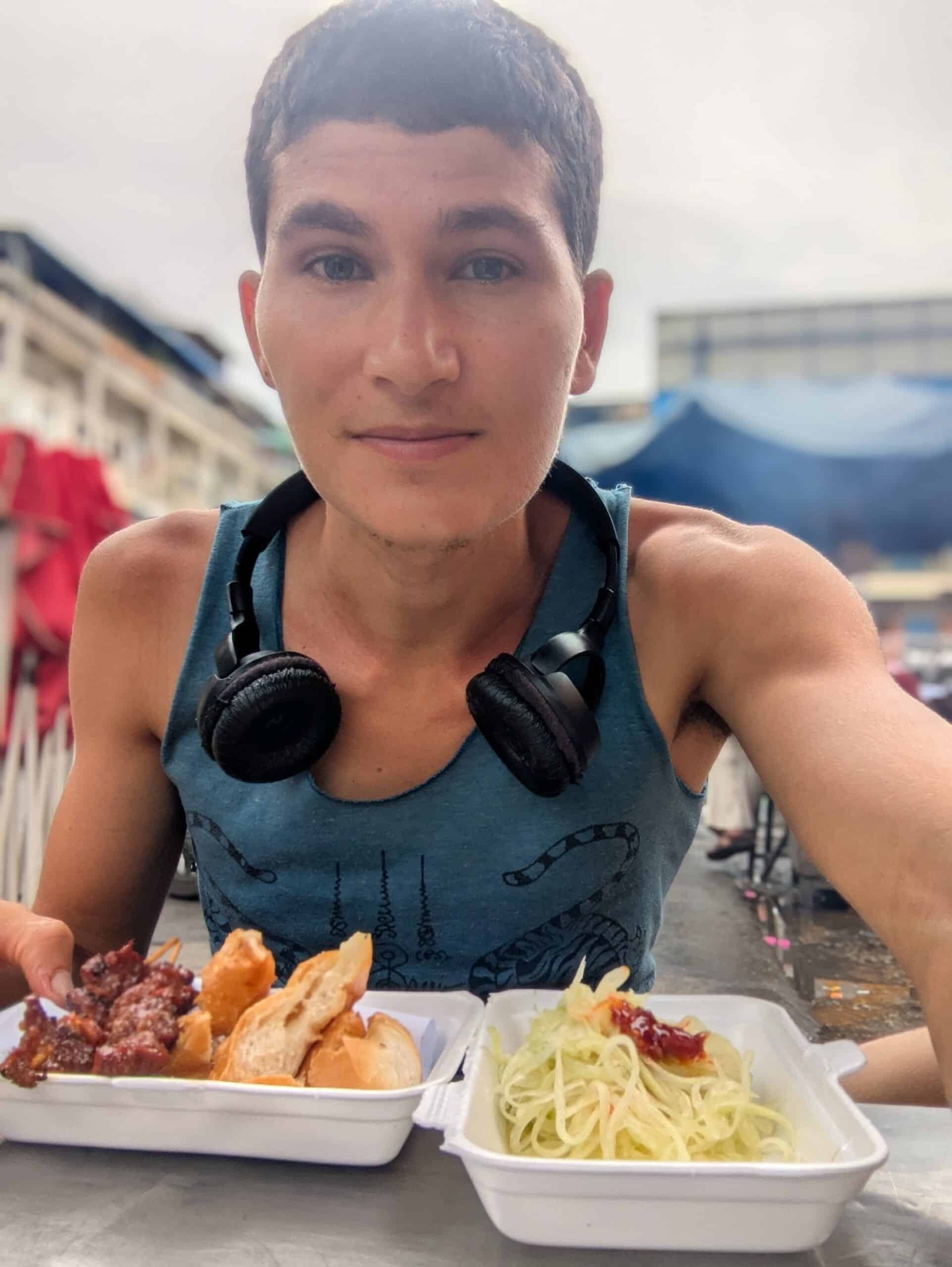 Oz Ilan enjoying pork skewers and green papaya salad at a street food stall in Phnom Penh.