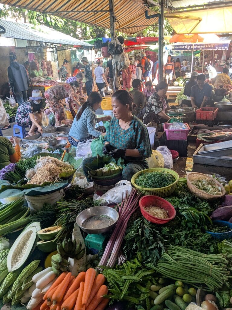 Phnom Penh fresh market with stalls of vegetables, herbs, and local produce.