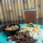 Cambodian chicken rice with egg strips, stir-fried greens, and spicy pickled vegetables.