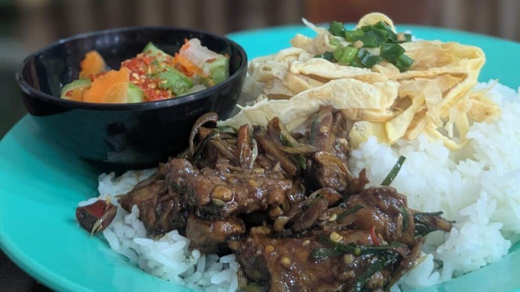 Cambodian chicken rice with egg strips, stir-fried greens, and spicy pickled vegetables.
