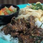 Cambodian chicken rice with egg strips, stir-fried greens, and spicy pickled vegetables.