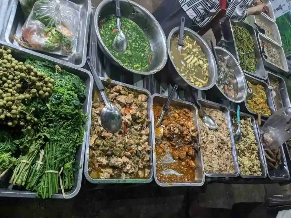 Lao Stews at Vang Vieng Market Assorted Lao stews in metal trays at Vang Vieng’s evening market, bursting with color and local flavor.